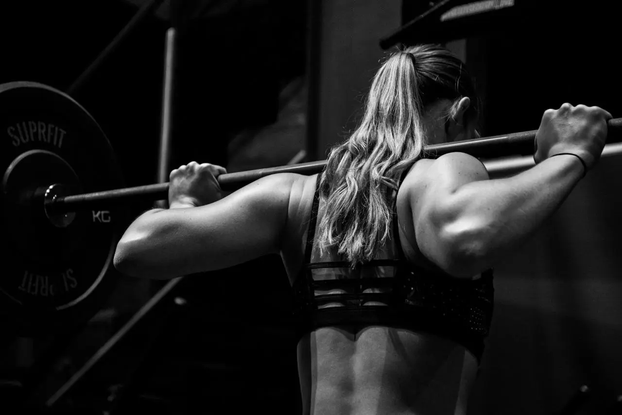 Woman lifting a barbell in a gym, black and white
